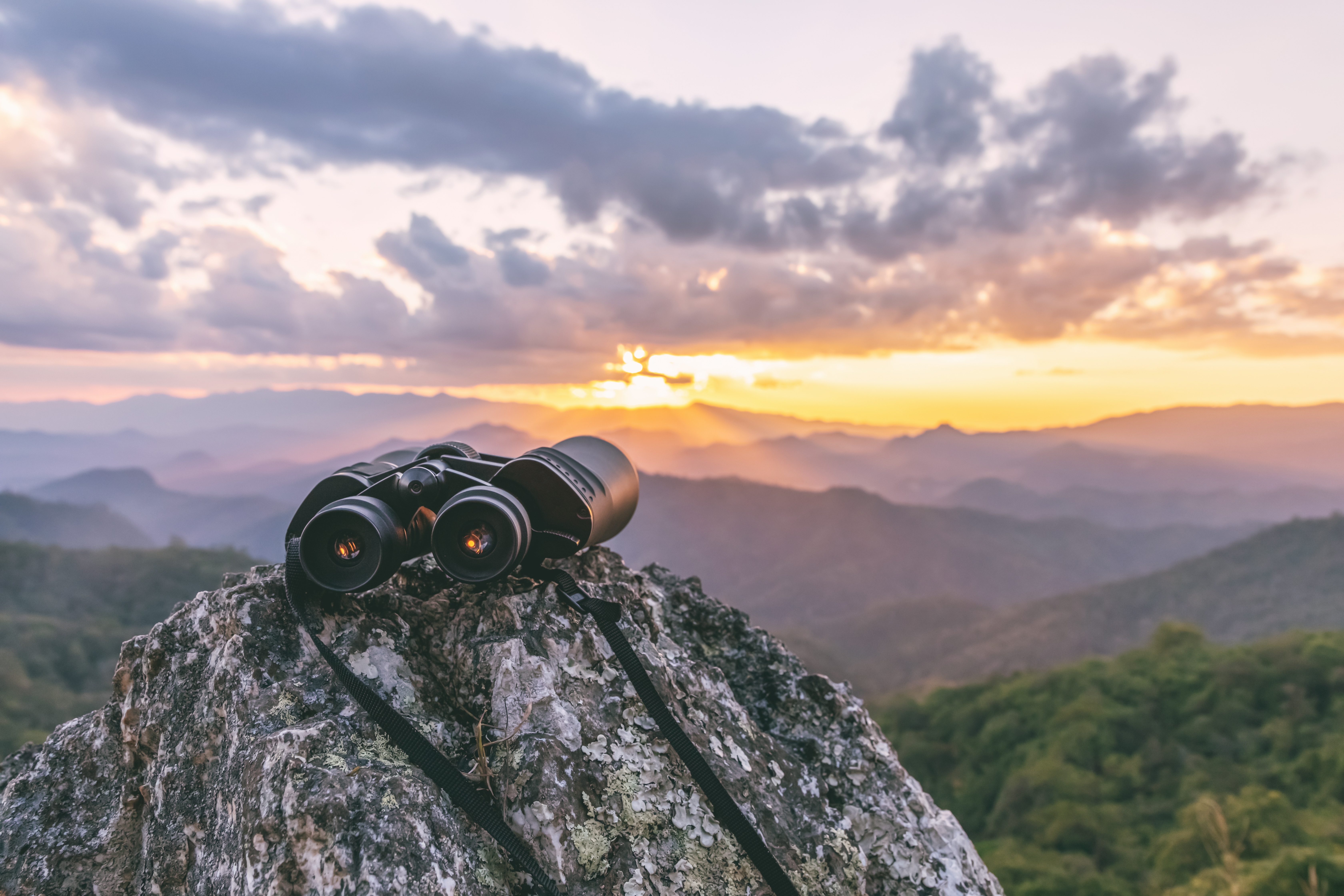 binoculars on top of rock mountain at sunset